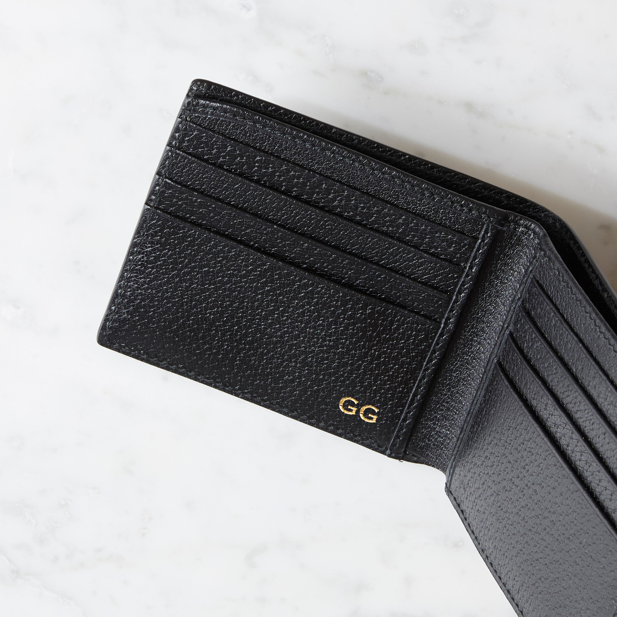 Gucci black wallet with Gucci logo embossed in gold.