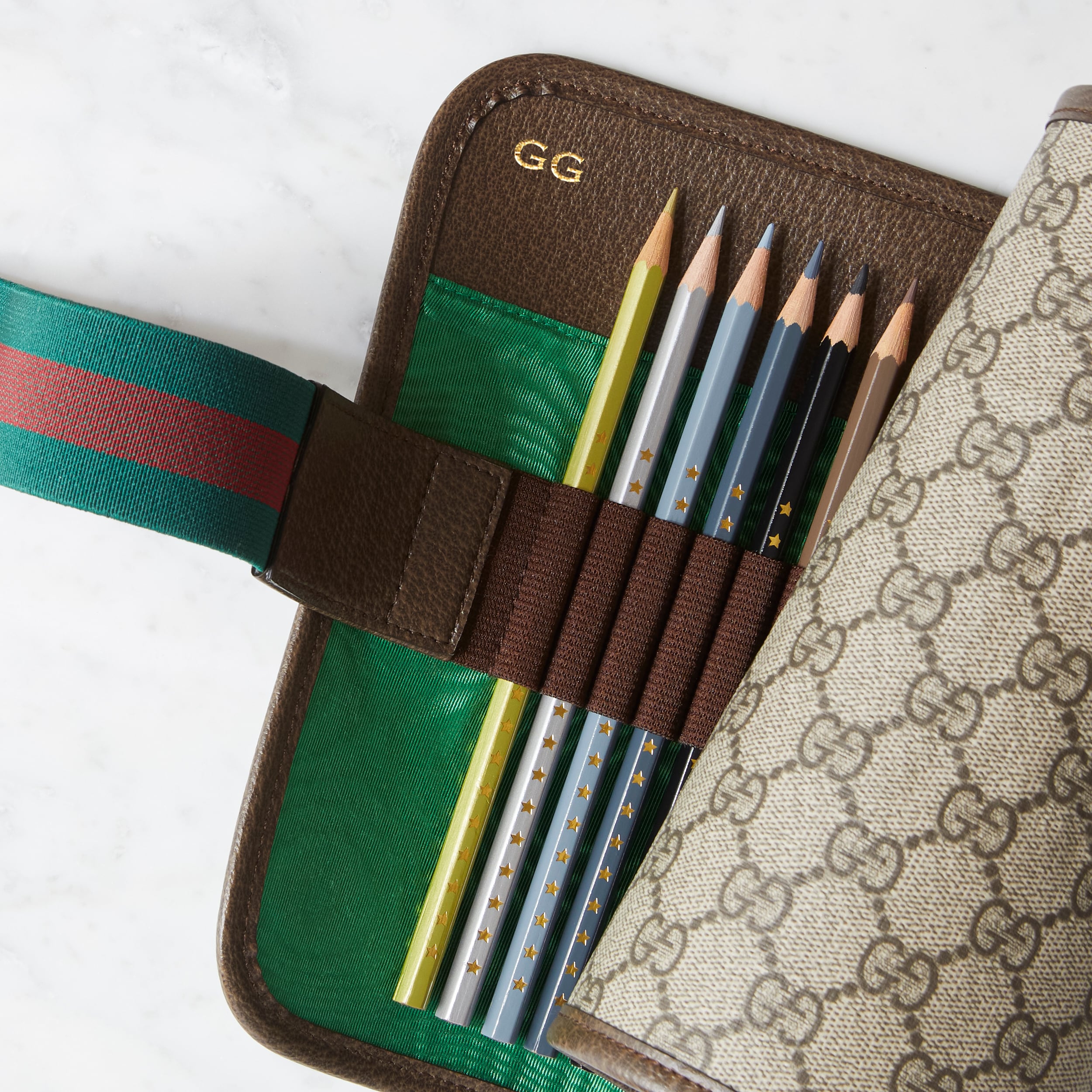 Trousse en toile GG Supreme Gucci avec bande Web vert et rouge et logo Gucci couleur or en relief.