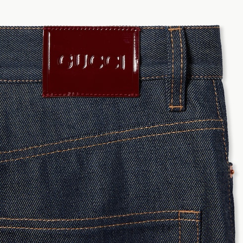 بنطال من قماش الجينز مع شعار Gucci مدروز بخيط الحواشي